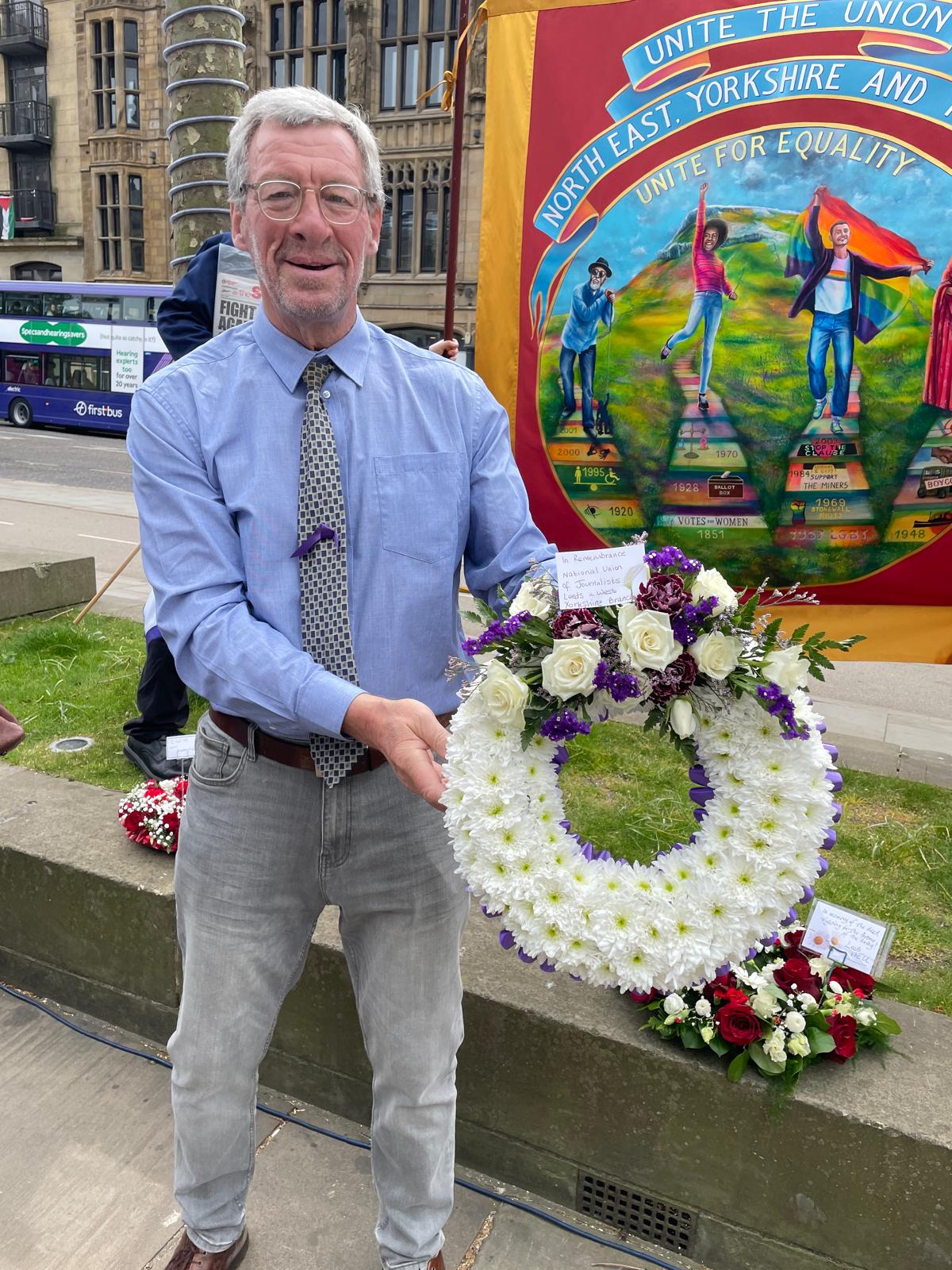 Neil Wilby holding the branch wreath in front of a Unite banner.