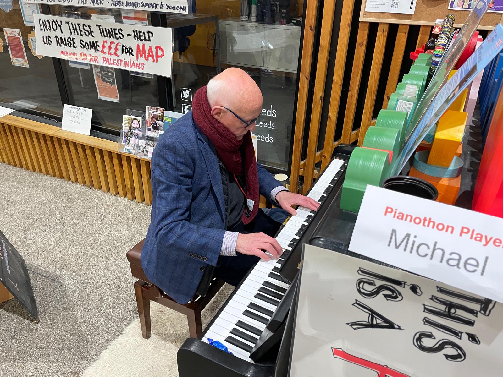 A man playing the piano with Michael written on a sign