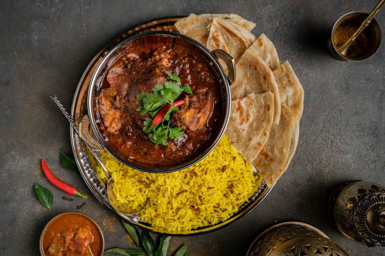 a bowl of curry, rice and pita bread