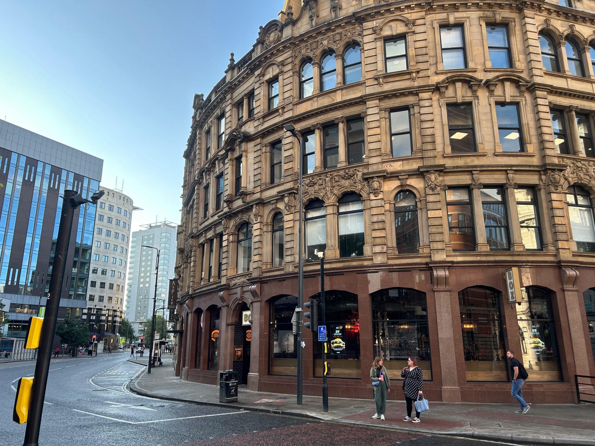 A grand looking four-storey building with detailed stonework and arched windows on the ground floor. The building curves round to the left, with road in front of it following the same line